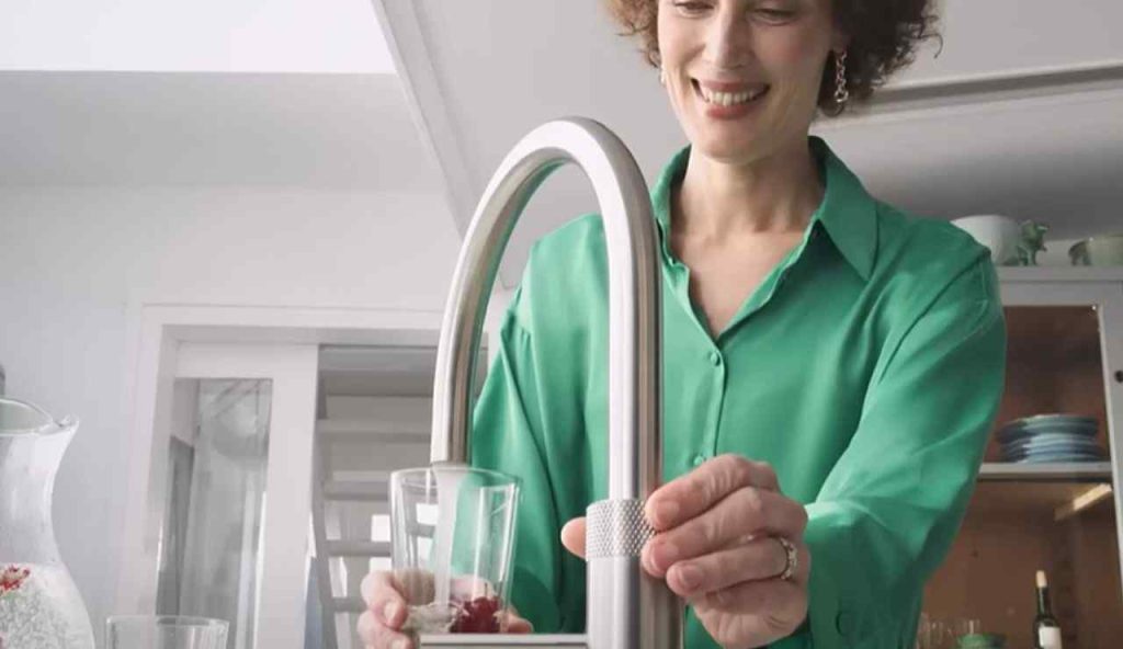 Donna che beve l'acqua dal rubinetto