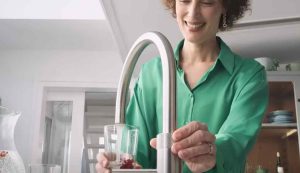 Donna che beve l'acqua dal rubinetto